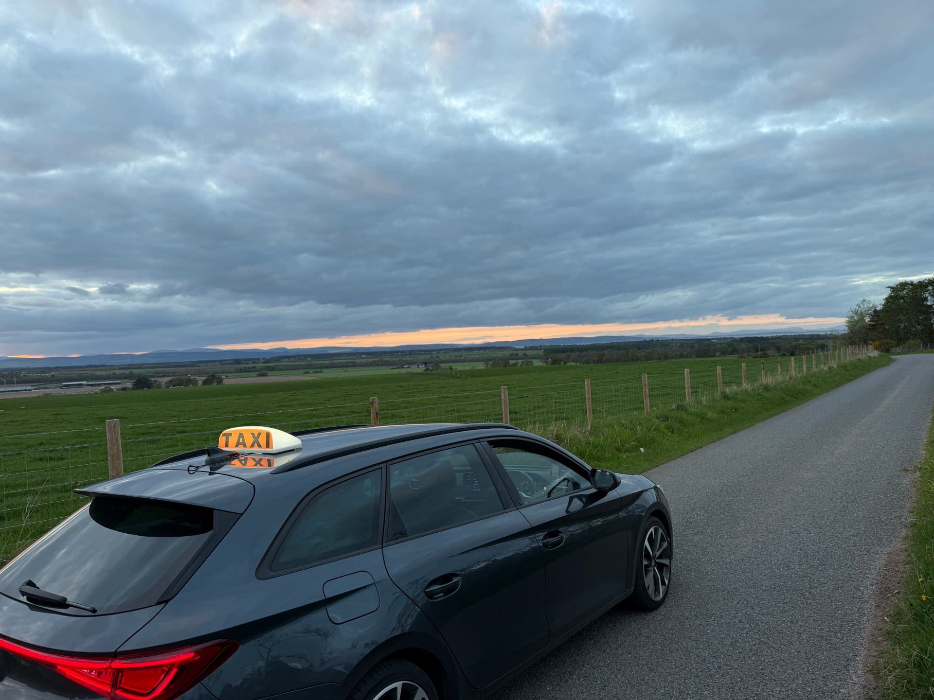A Moray Taxis Nairn car on a country road at dusk