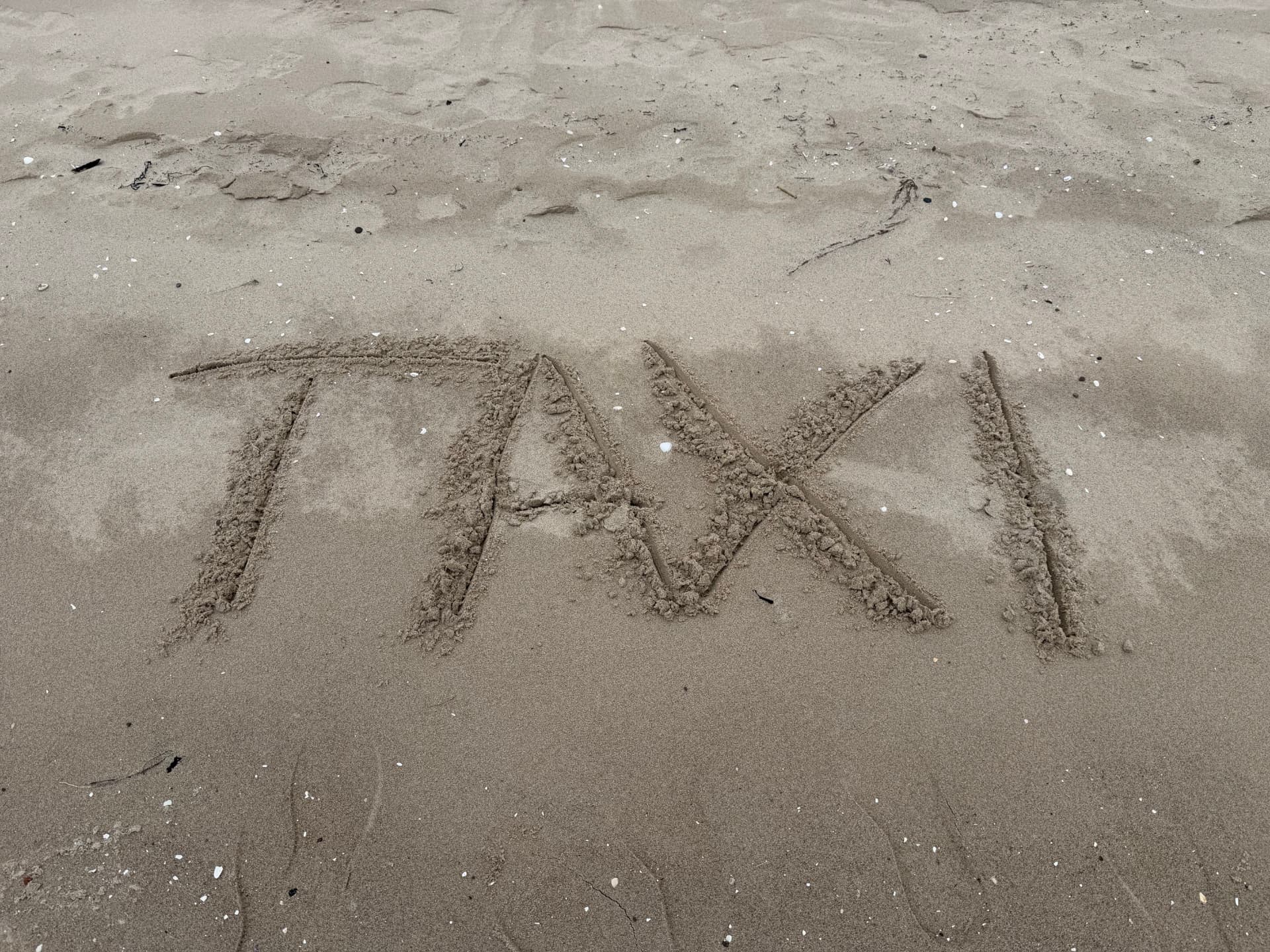 TAXI written in the sand on Nairn beach